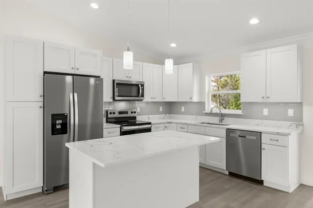 a kitchen with a sink a stove a refrigerator a center island and a window