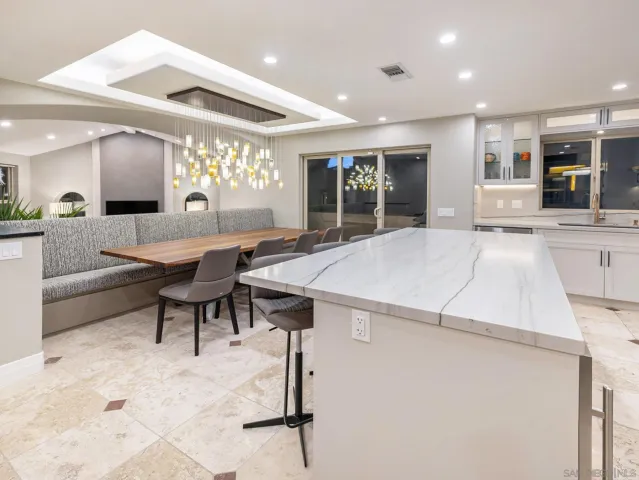 a kitchen with stainless steel appliances granite countertop a table chairs sink and cabinets