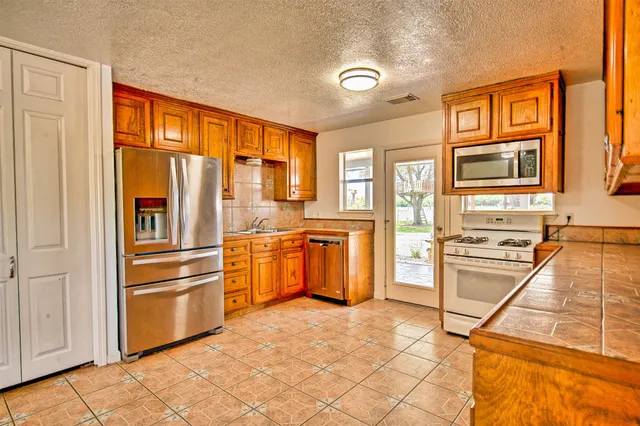 a view of a kitchen with stainless steel appliances granite countertop a refrigerator and cabinets