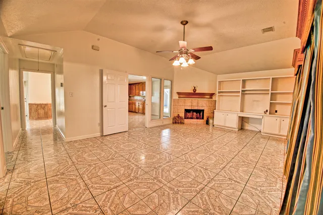 a view of a livingroom with a fireplace a chandelier and windows
