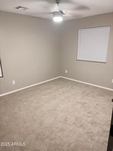 an empty room with a fan & a window