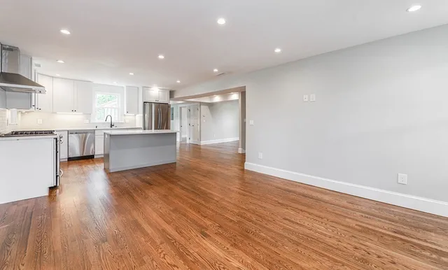 a view of kitchen with cabinets wooden floor and stainless steel appliances