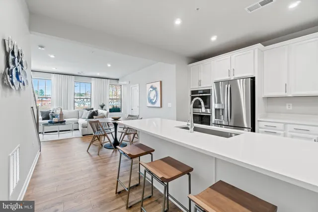 a living room with stainless steel appliances furniture a flat screen tv and a refrigerator