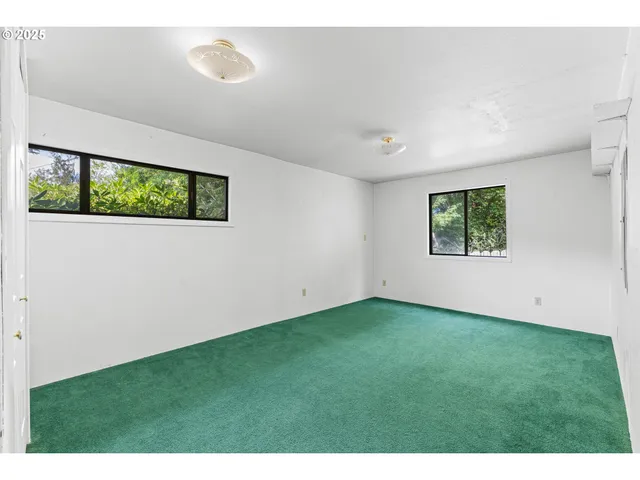 a view of an empty room with a window and kitchen view