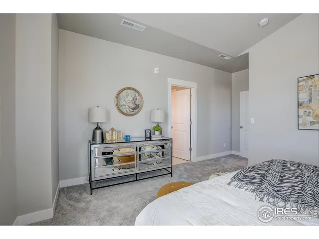 a bedroom with a bed and a lamp on dresser