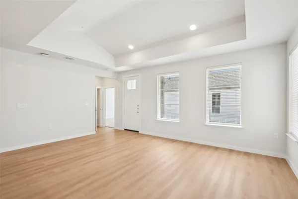 an empty room with wooden floor and windows