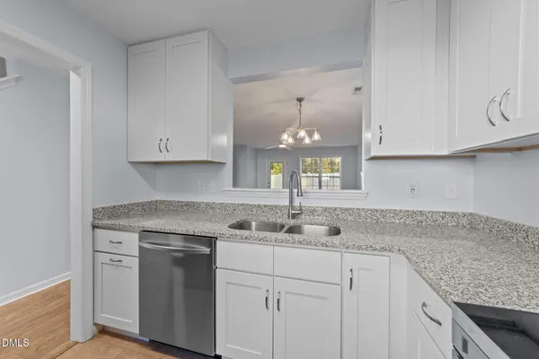a kitchen with granite countertop white cabinets and a sink