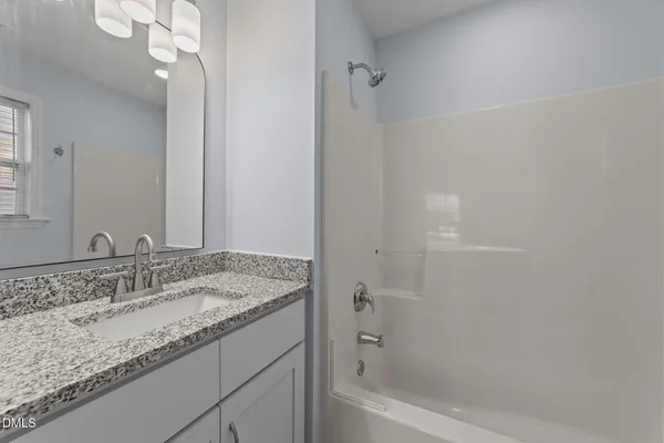 a bathroom with a granite countertop sink a mirror and a bathtub