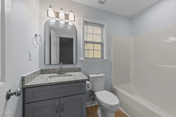 a bathroom with a granite countertop toilet a sink and a mirror