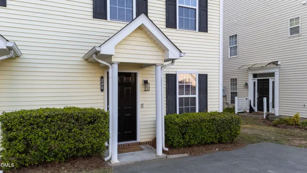 a view of a white house with a small yard and plants
