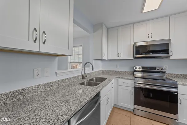 a kitchen with granite countertop a sink dishwasher stove and microwave with wooden cabinets