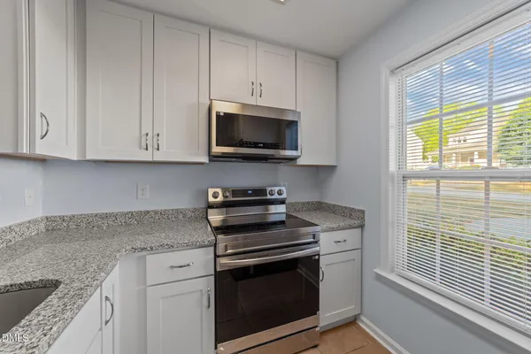 a kitchen with granite countertop cabinets stainless steel appliances and a window