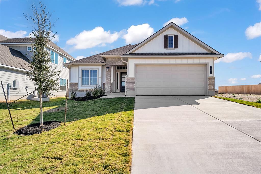 View of front facade featuring brick siding, concrete driveway, and board and batten siding