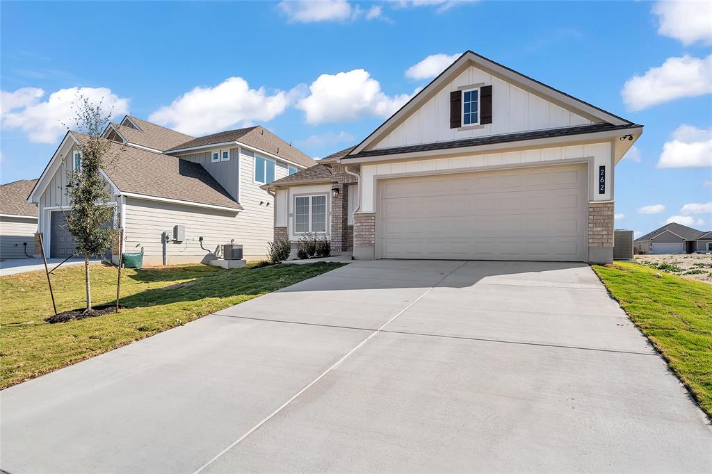 262 Boatright Boulevard Jarrell, TX 76537 - Photo 3 of 30 View of front of property with board and batten siding, concrete driveway, a front lawn, brick siding, and an attached garage