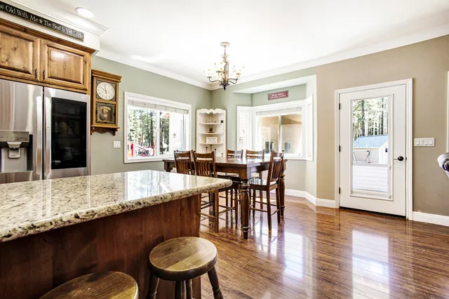 a dining room with wooden floor a chandelier a wooden table and chairs