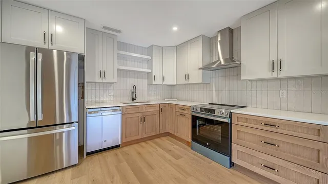 a kitchen with stainless steel appliances white cabinets and wooden floors