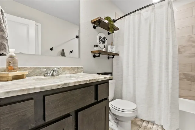 a bathroom with a granite countertop sink toilet and a mirror
