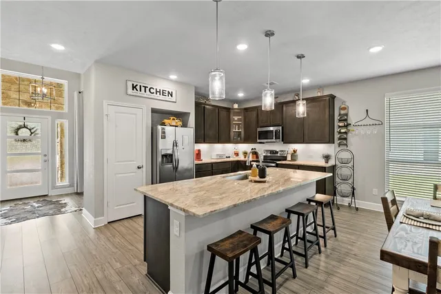 a kitchen with stainless steel appliances kitchen island granite countertop a table chairs sink and wooden floor