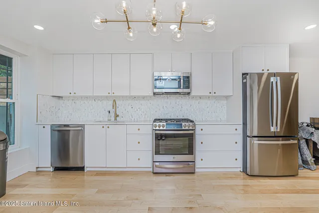 a kitchen with a refrigerator a microwave oven a sink and chairs