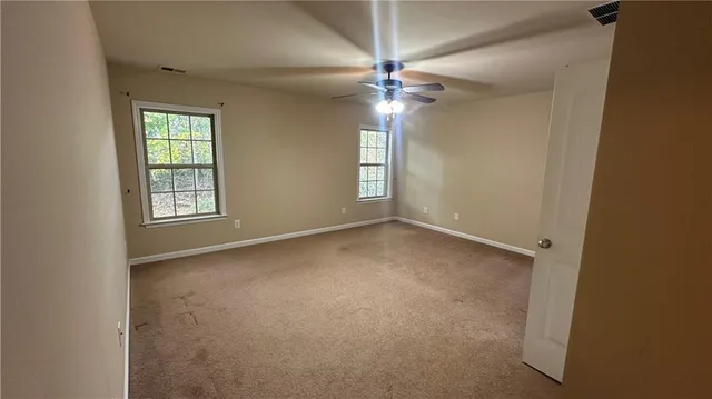 an empty room with a window and a fan