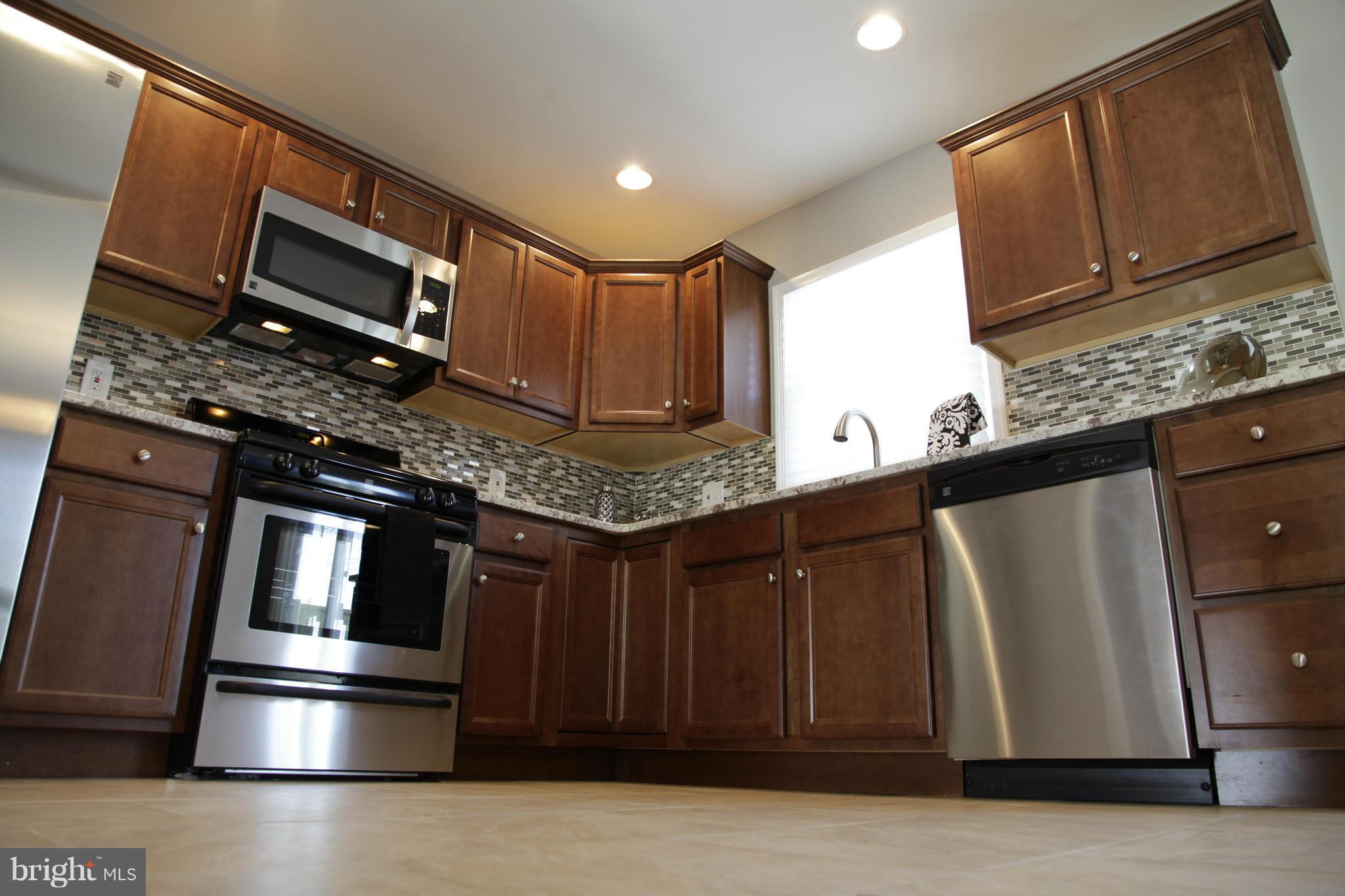3344 Ripple Road Windsor Mill, MD 21244 - Photo 3 of 30 a kitchen with stainless steel appliances granite countertop a refrigerator and wooden cabinets