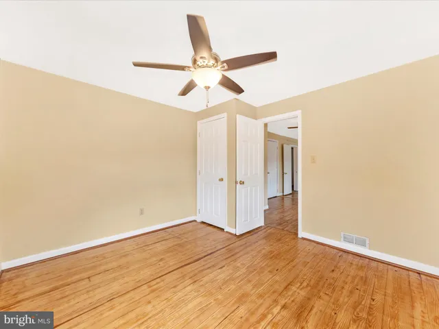 a view of a room with wooden floor and ceiling fan