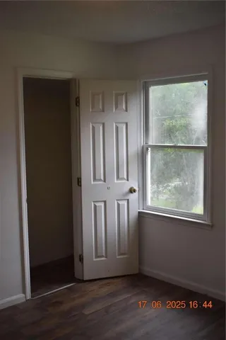 an empty room with wooden floor cabinet and windows
