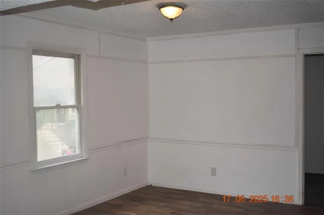 a view of an empty room with wooden floor and windows