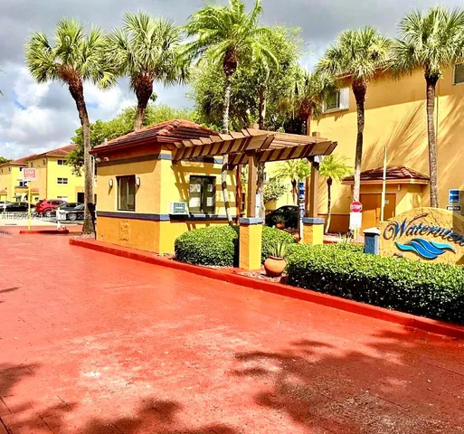a view of a white house with a big yard and palm trees