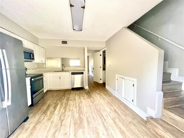 a kitchen with a sink a refrigerator and cabinets