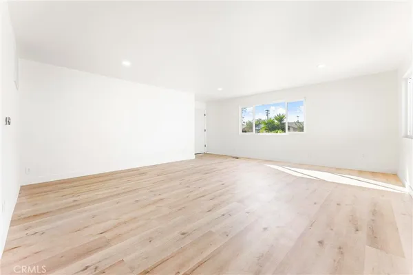 an empty room with wooden floor and window
