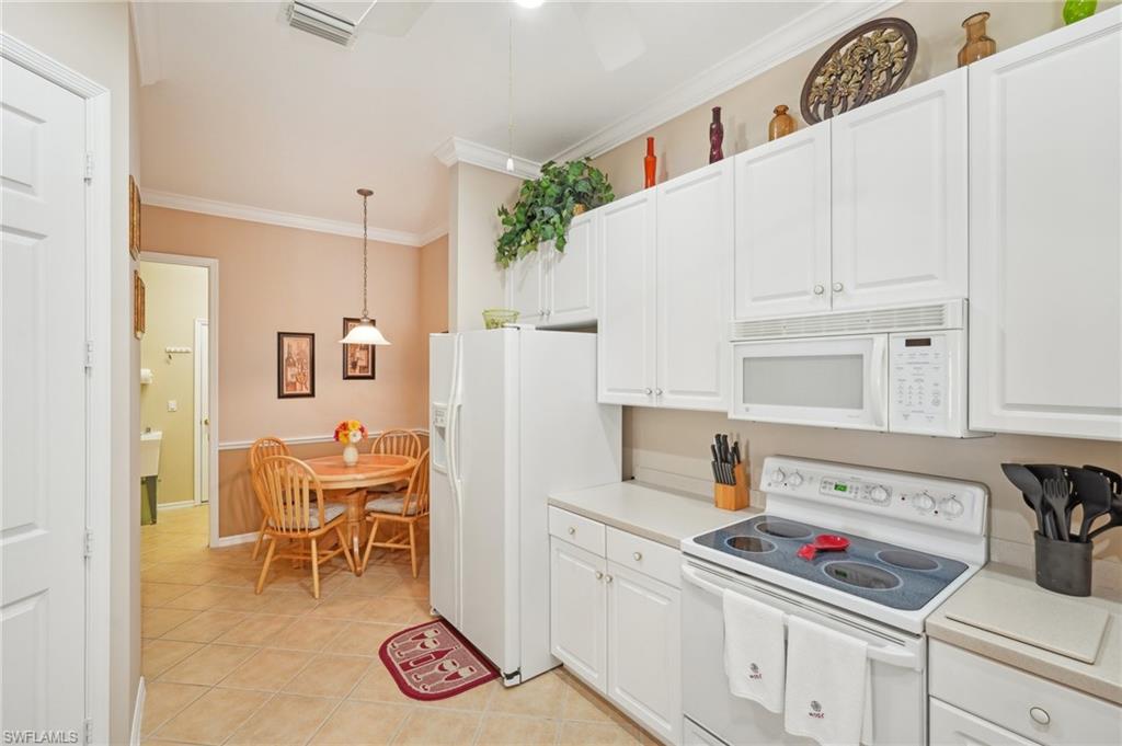 3553 Periwinkle Way Naples, FL 34114 - Photo 14 of 43 Kitchen with pendant lighting, light countertops, white cabinetry, and white appliances