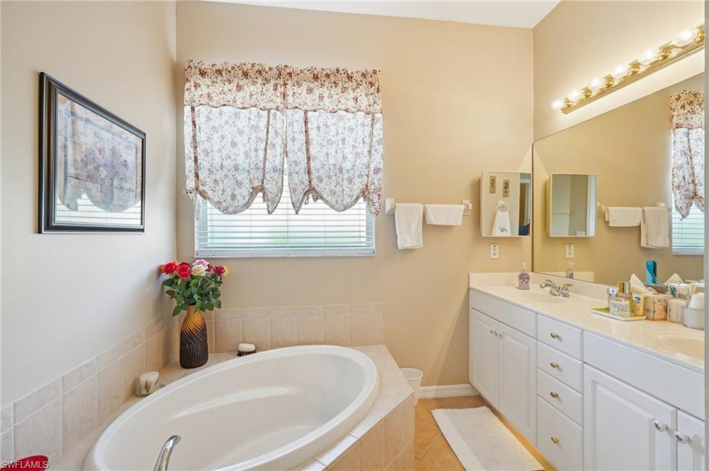 3553 Periwinkle Way Naples, FL 34114 - Photo 29 of 43 Bathroom with a sink, a garden tub, baseboards, double vanity, and tile patterned flooring