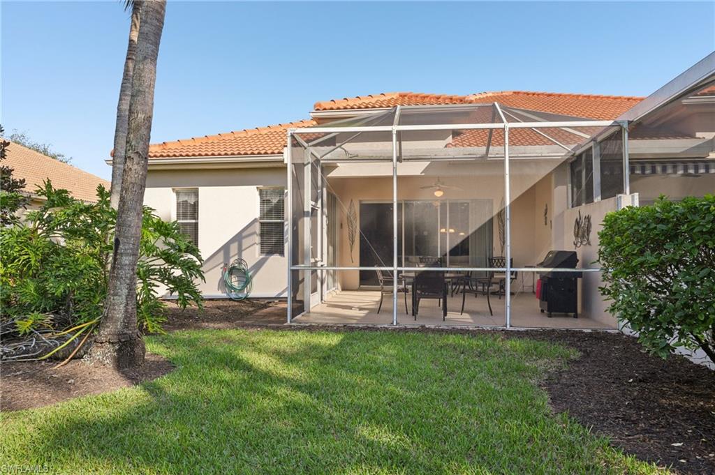 3553 Periwinkle Way Naples, FL 34114 - Photo 33 of 43 Rear view of property featuring glass enclosure, a ceiling fan, a patio area, a yard, and a tile roof