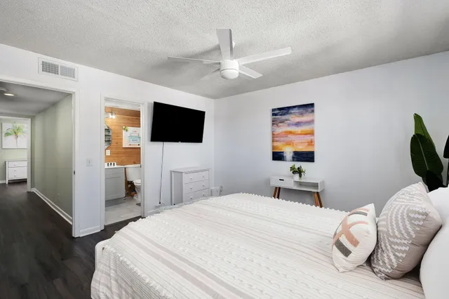 a bedroom with a bed and a flat tv screen on dresser