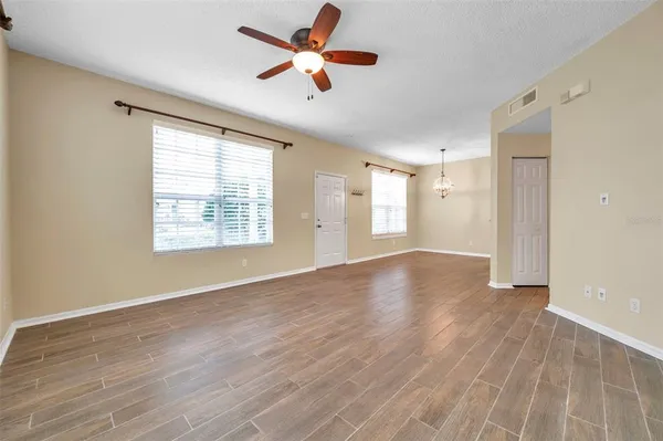 a view of an empty room with a window and wooden floor