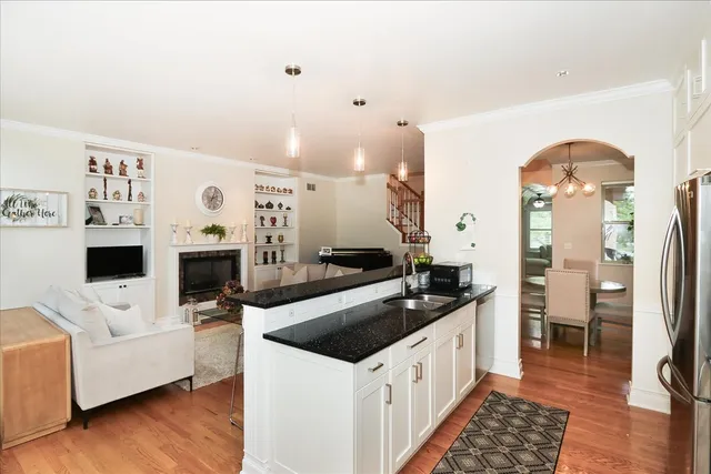 a kitchen with stainless steel appliances a stove a sink and white cabinets with wooden floor
