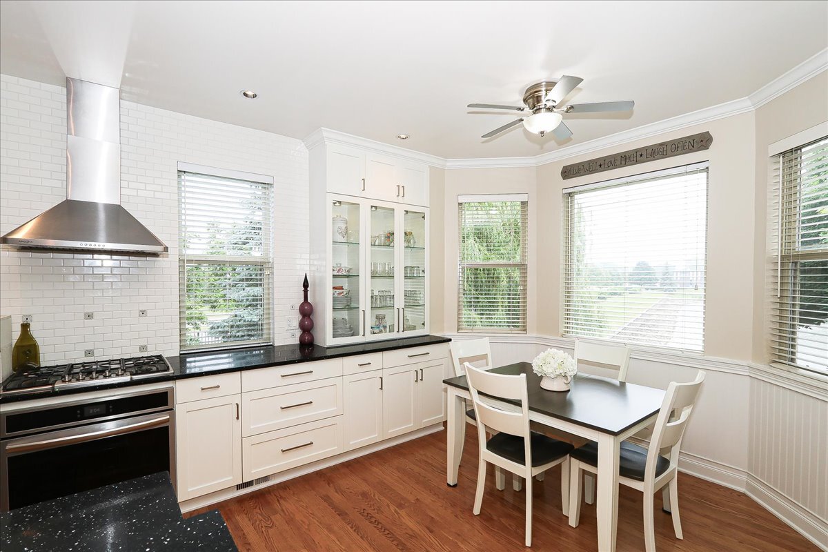768 St Johns Place Addison, IL 60101 - Photo 20 of 39 a kitchen with stainless steel appliances granite countertop a stove a sink dishwasher a dining table and chairs with wooden floor