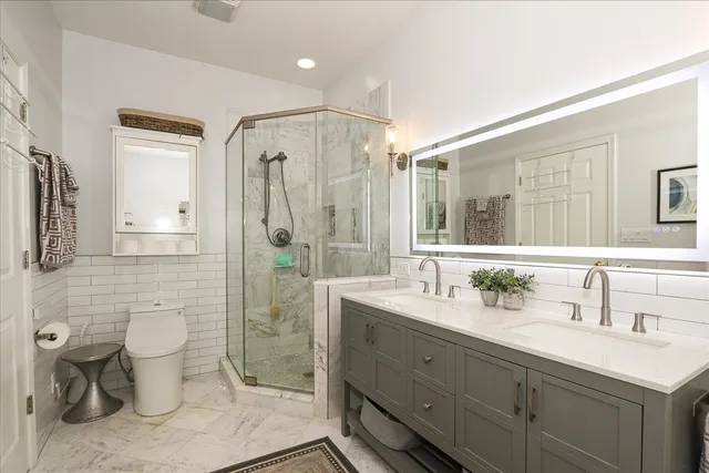 a bathroom with a double vanity sink toilet and shower