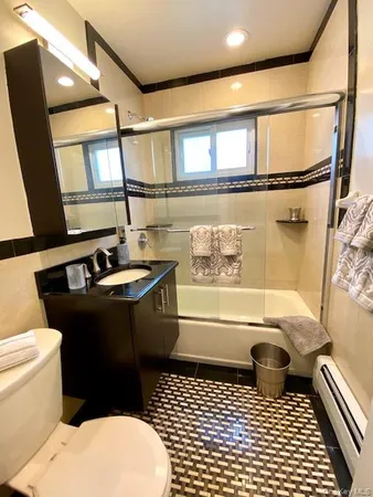 a bathroom with a sink a toilet a mirror a bathtub and shower
