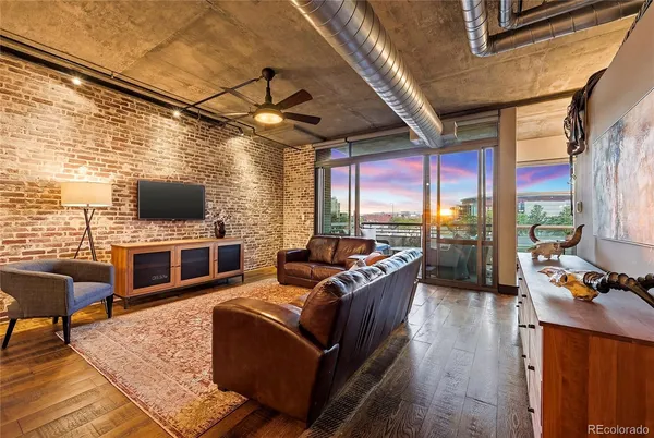 a living room with furniture a flat screen tv and floor to ceiling window