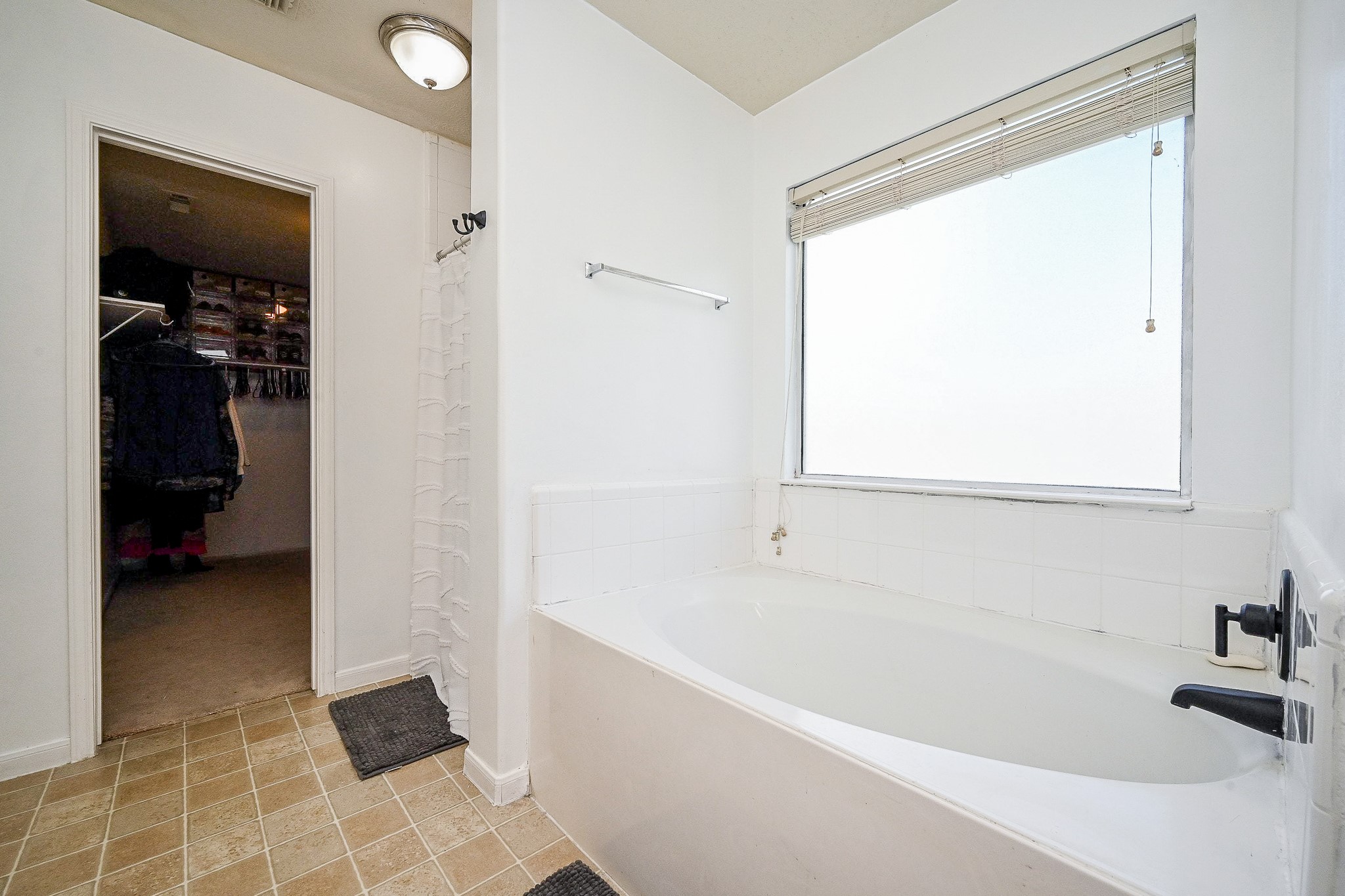 2534 Halstead Drive Spring, TX 77386 - Photo 28 of 35 This bathroom features a spacious bathtub with a large frosted window for natural light. It connects to a walk-in closet, providing convenient access and ample storage space. The room is bright and functional, perfect for relaxing and organizing.