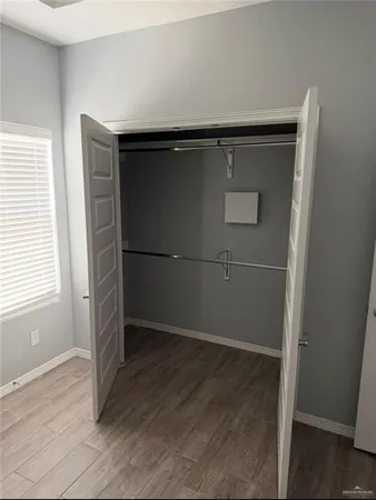 an empty room with wooden floor and window
