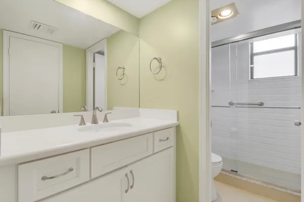 a bathroom with a granite countertop sink mirror vanity and toilet
