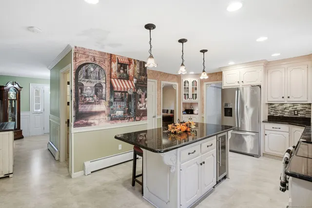 a kitchen with stainless steel appliances kitchen island granite countertop a refrigerator and cabinets
