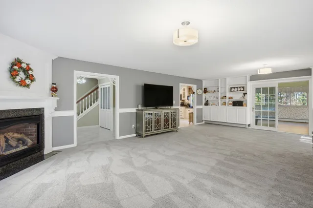 a view of a livingroom with a fireplace a flat screen tv and staircase