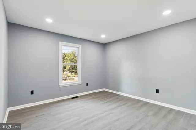 an empty room with wooden floor and window