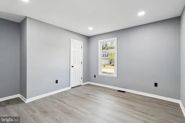 an empty room with wooden floor and window