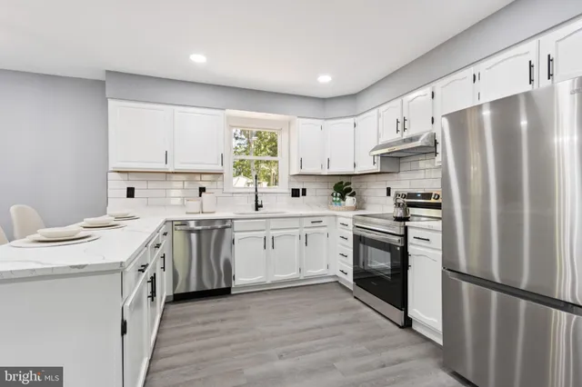 a kitchen with white cabinets stainless steel appliances and sink