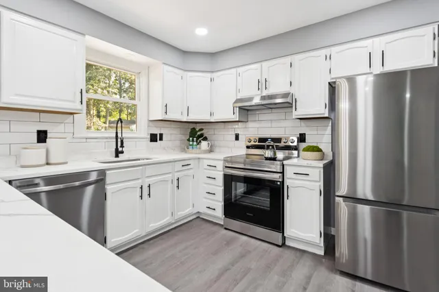 a kitchen with stainless steel appliances a refrigerator sink and cabinets